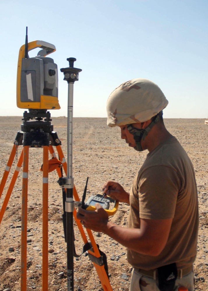 Surveyor operating a Trimble robotic total station in the field
